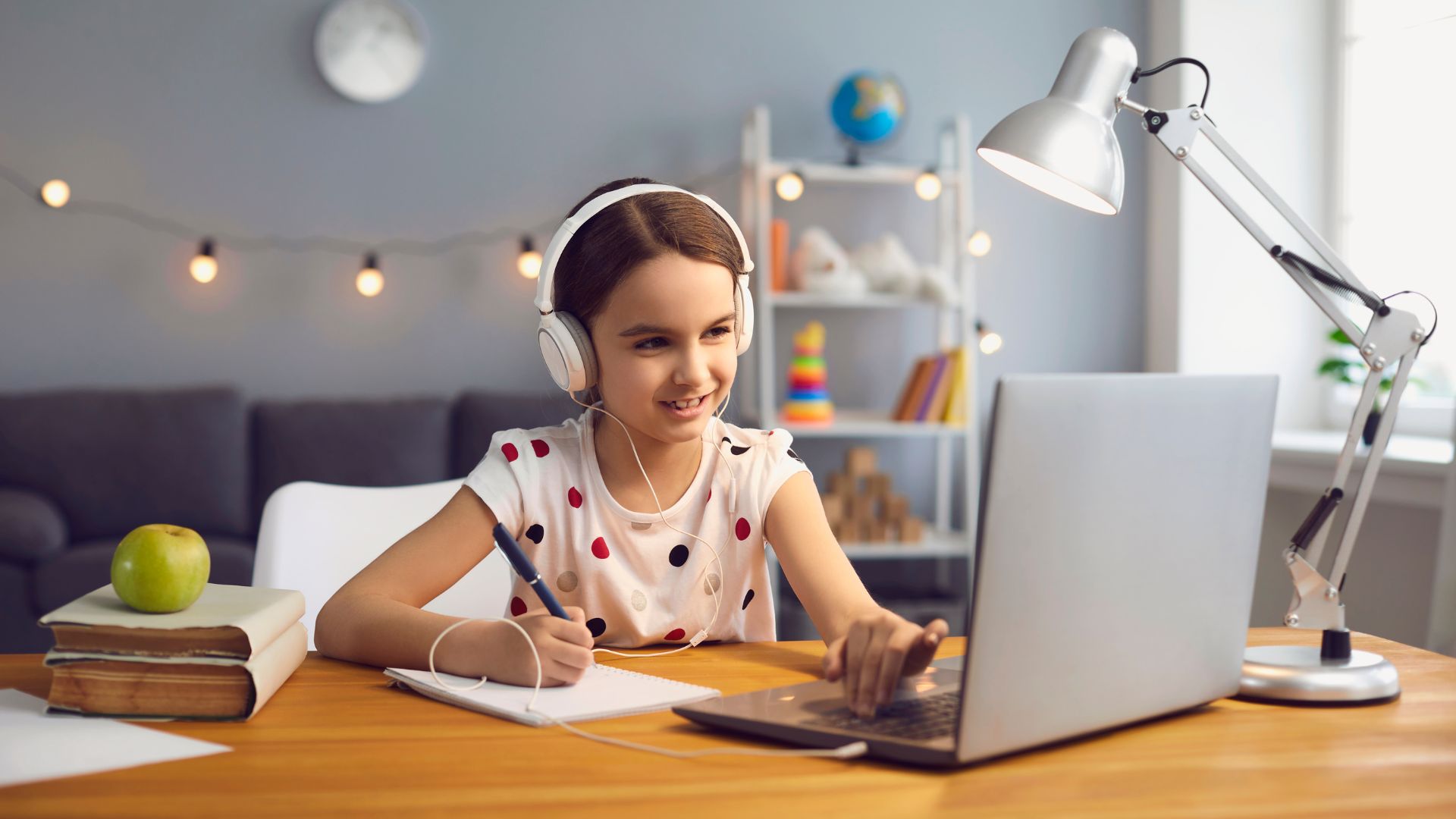 Young girl wearing headphones and using her laptop to learn online