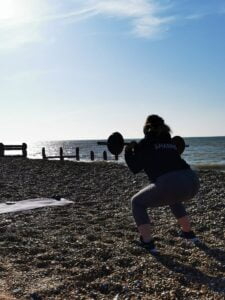 A lady lifting weights on on the beach
